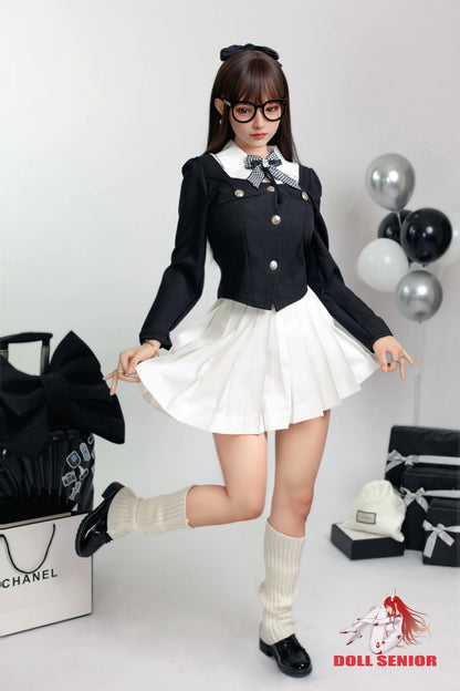 Realistic female doll in black and white school uniform with pleated skirt, glasses, and knee-high socks, posing playfully.