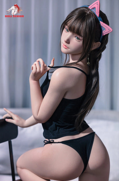 Realistic female doll with brown hair, green eyes, wearing black lingerie and pink cat ears, seated on chair.