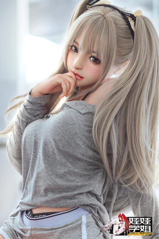 Realistic female doll with long blonde hair in pigtails, wearing gray top and headband, posing thoughtfully.