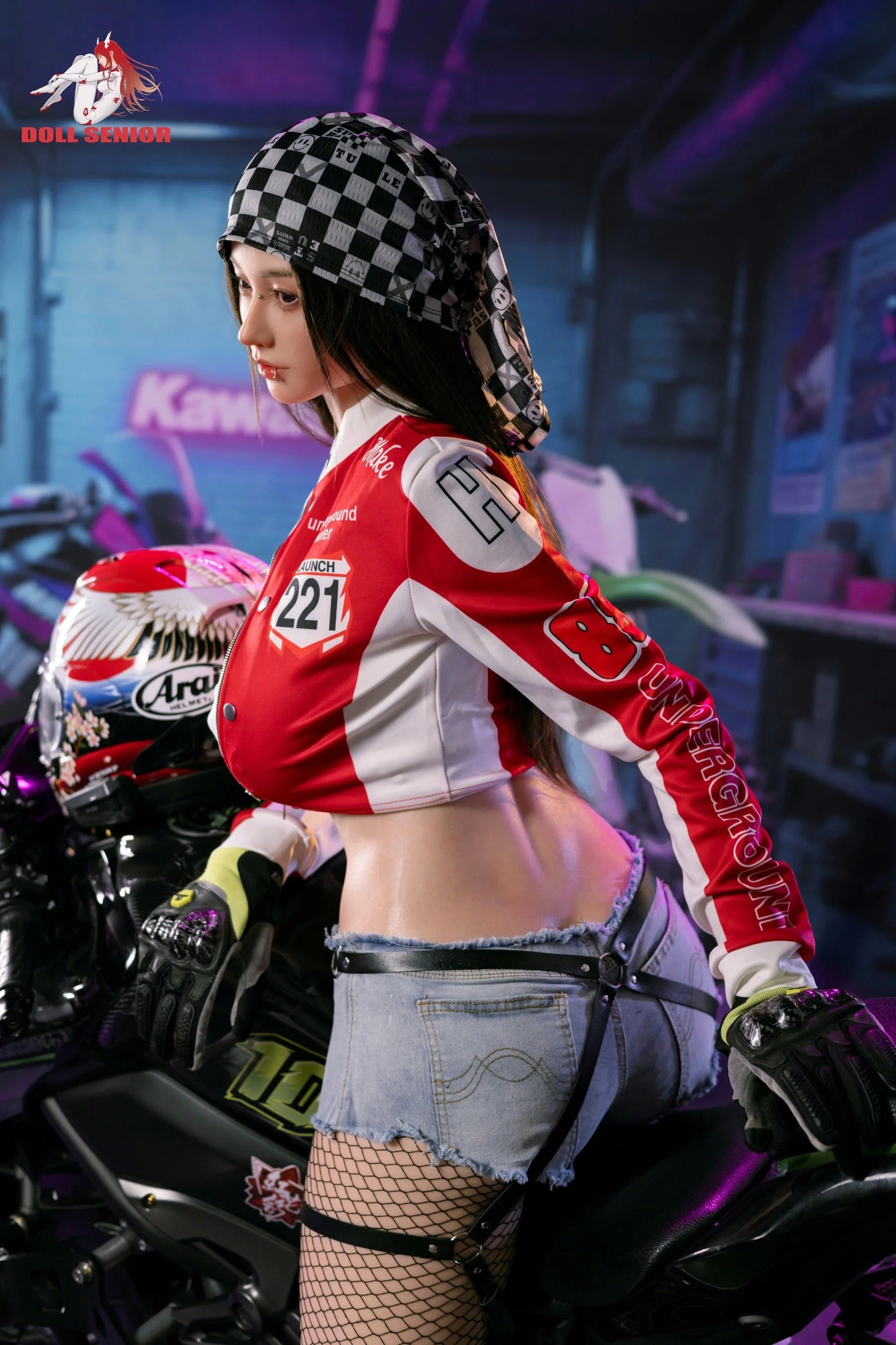 Realistic female doll in red racing jacket, checkered bandana, denim shorts, and fishnet stockings, posed on motorcycle.