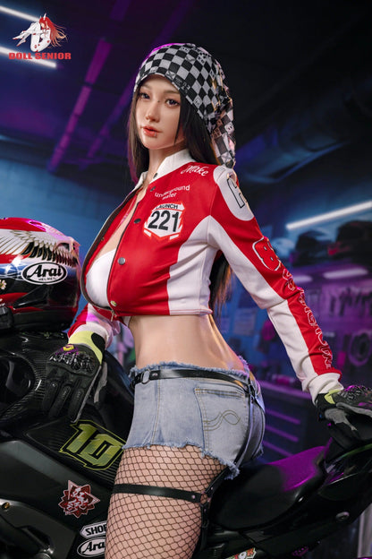 Realistic female figure in red racing jacket, denim shorts, fishnet stockings, posed on motorcycle with checkered hood and Arai helmet nearby