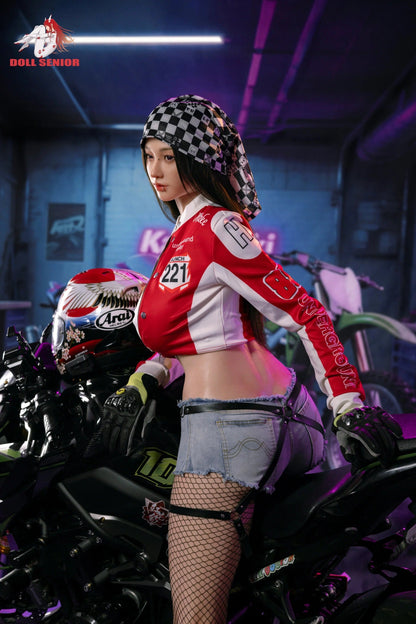 Realistic female doll in red racing jacket, denim shorts, fishnet stockings, leaning on motorcycle in neon-lit garage