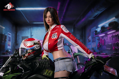 Realistic female doll in red racing jacket and denim shorts, posed on motorcycle in neon-lit garage