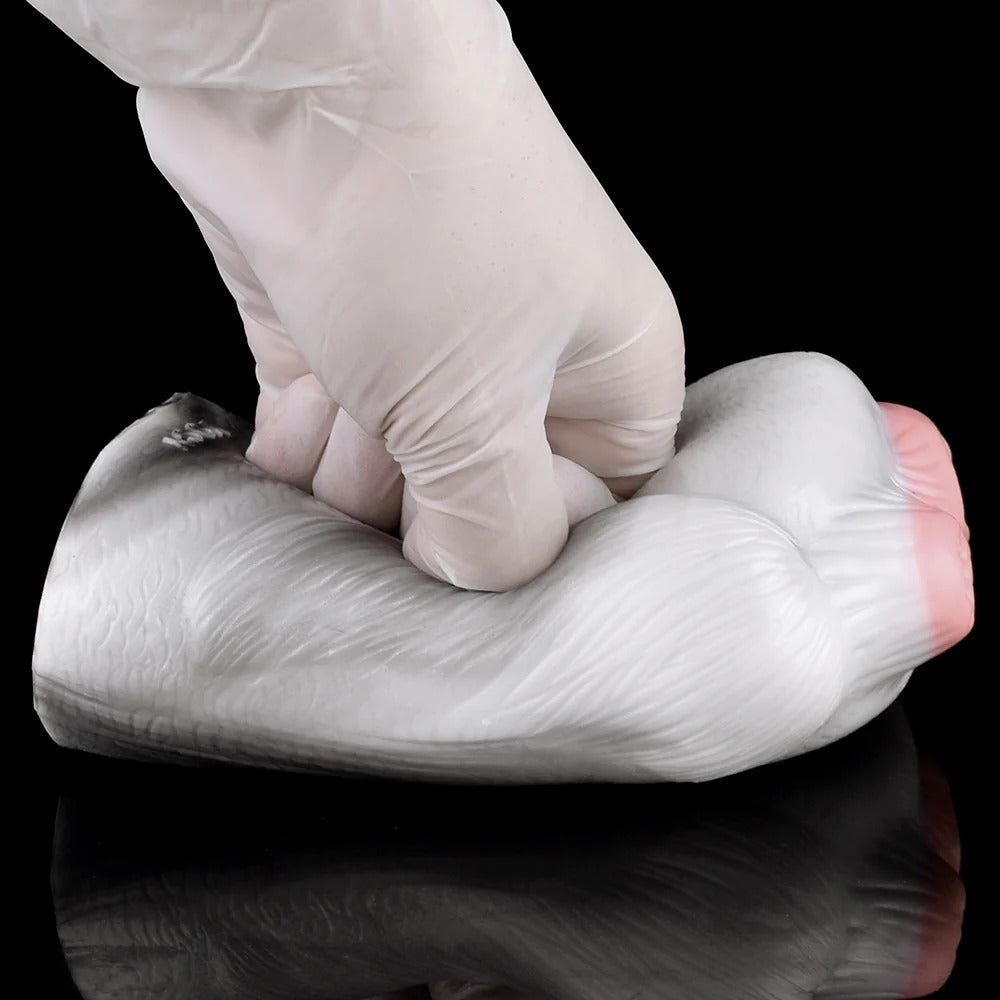 Realistic male masturbator with soft, textured silicone skin and natural pink tones, shown being gently pressed for flexibility demonstration.