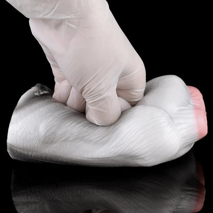 Realistic male masturbator with soft, textured silicone skin and natural pink tones, shown being gently pressed for flexibility demonstration.