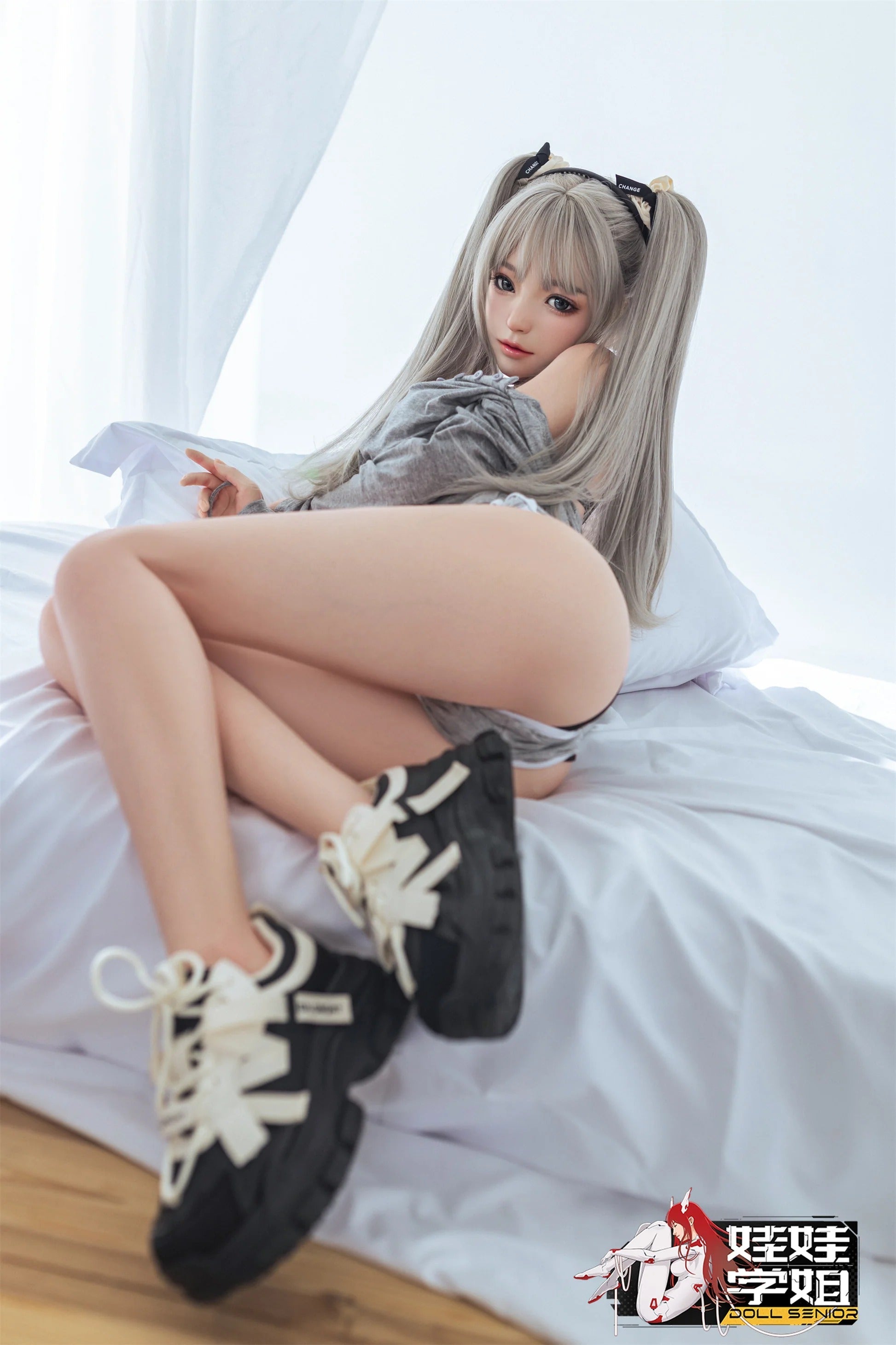 Realistic female doll with silver twin tails, gray top, black sneakers, lounging on white bed