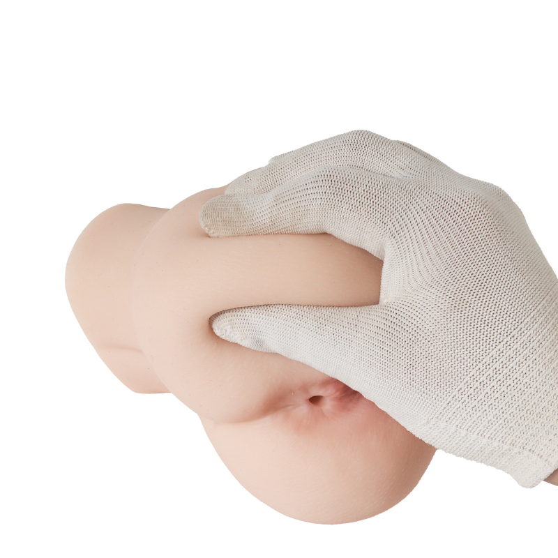 Soft silicone male masturbator with realistic skin texture and natural curves, shown with gloved hand for scale.